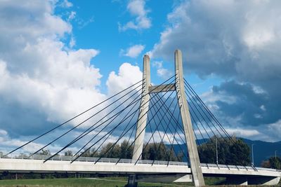 Low angle view of suspension bridge against cloudy sky