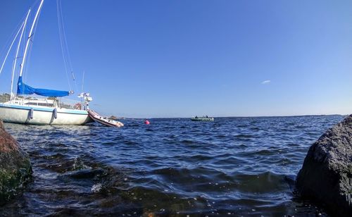 Sailboat sailing on sea against clear blue sky