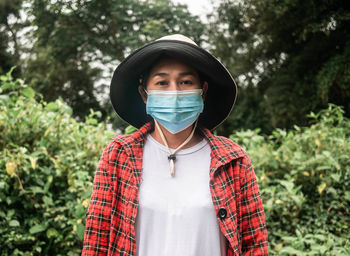 Portrait of woman wearing mask standing against plants