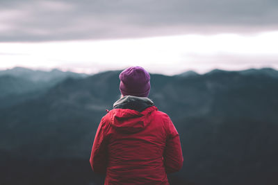 Rear view of man standing on mountain against sky