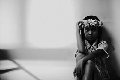 Portrait of girl sitting against wall at home