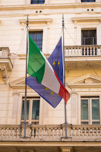 Low angle view of flags waving on building in city