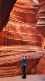 Young man photographing while standing in cave