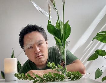 Young asian man with aroma diffuser, peace lilies and plants.