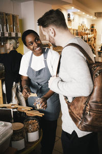 Smiling female owner discussing with customer while working in store