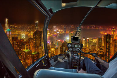 Illuminated cityscape against sky at night seen through helicopter