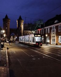 Cars on road by illuminated buildings in city at night