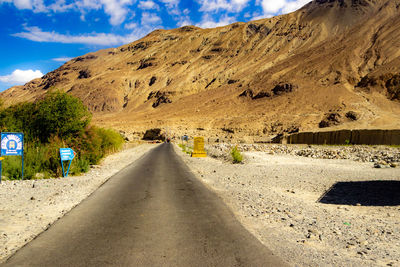 Road leading towards mountains against sky