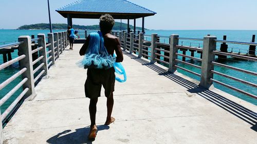 Rear view of fisherman with net walking on pier