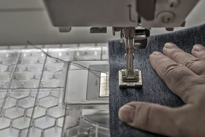 Close-up of hand sewing fabric with machine