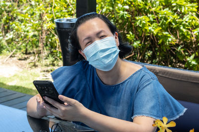 Portrait of smiling woman wearing mask while using mobile phone