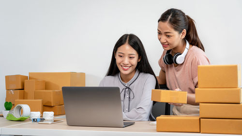 Portrait of woman using laptop while sitting on sofa against white background