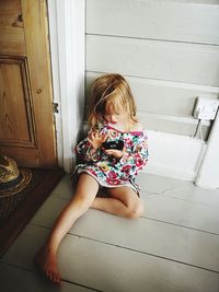 Full length of girl using mobile phone at doorway