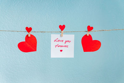 Close-up of heart shape text on paper against wall