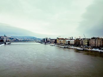 Bridge over river by buildings in city against sky