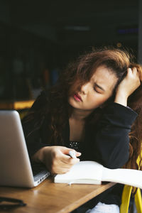 Young woman using phone on table