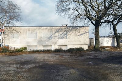 Bare tree by building against sky