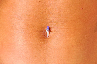 Midsection of woman with flower on belly button