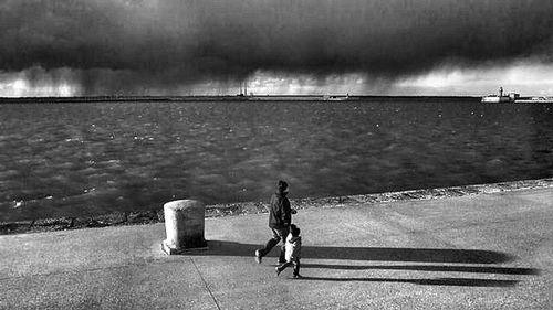 Woman standing on beach against cloudy sky