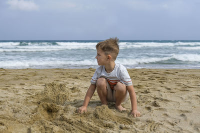 Full length of boy on beach against sky