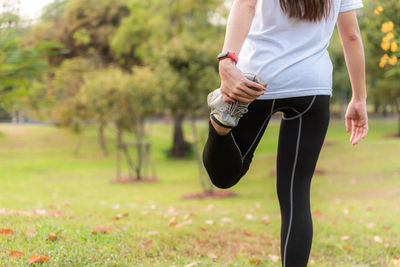 Midsection of woman stretching leg outdoors