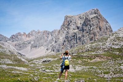 Full length of a hiker woman taking a picture of the mountains