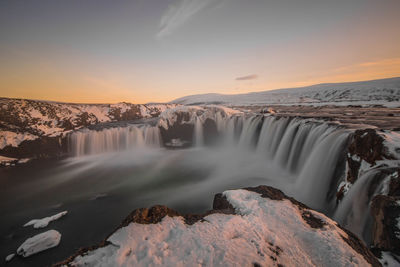 Scenic view of waterfall against sky during sunset