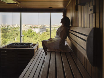 Senior woman sitting on wooden sauna at health spa