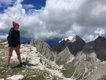 Full length of young woman standing on rock against sky