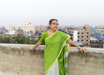 An aged bengali woman enjoying view of urban surroundings from rooftop of a building at howrah india