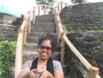 Portrait of young woman on steps in city