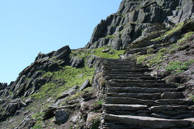 Low angle view of steps by mountain against clear sky
