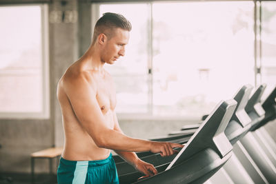 Shirtless man exercising on treadmill