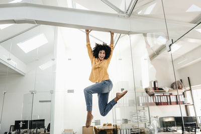 Happy young woman hanging on beam in office