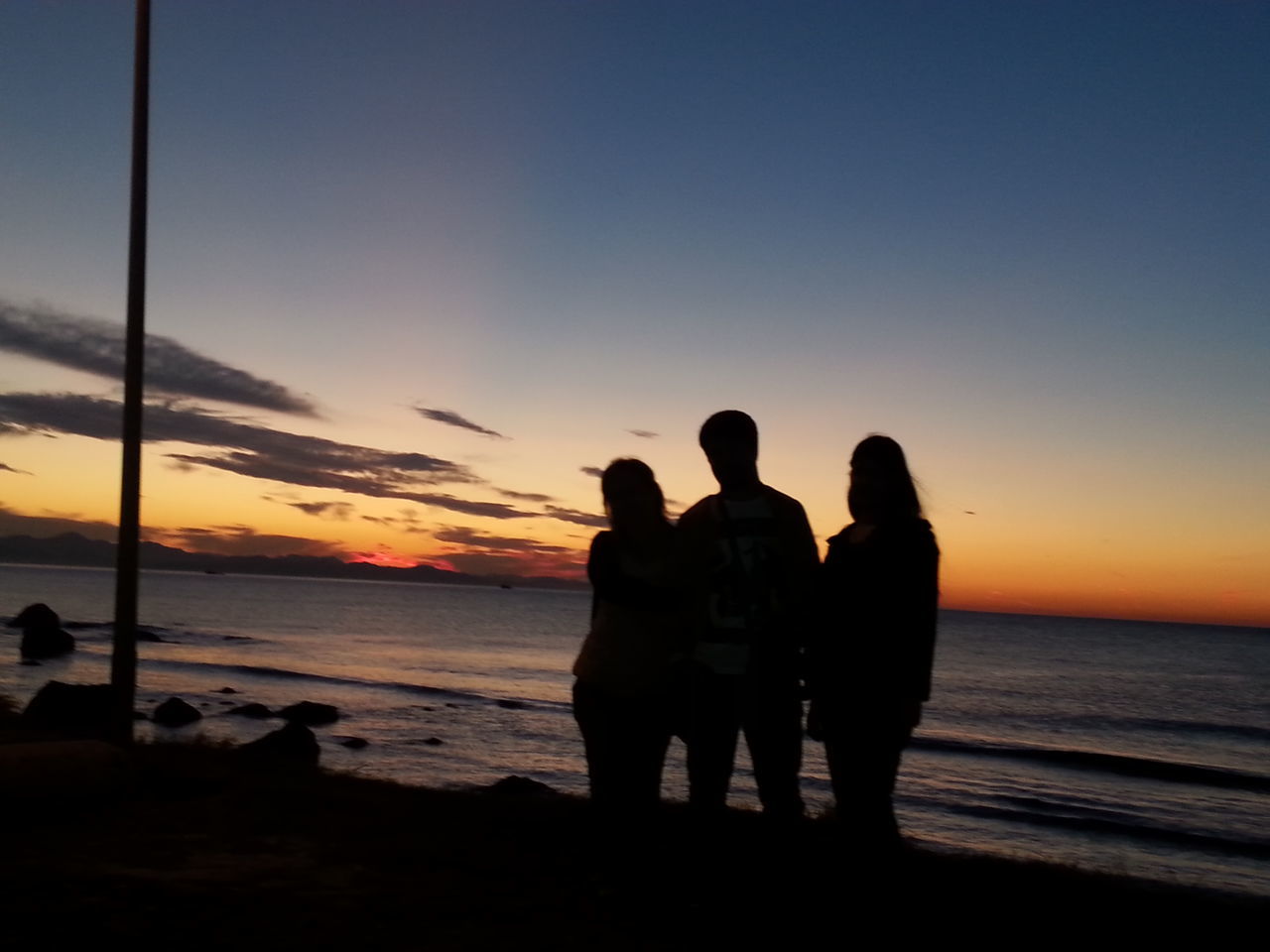 sunset, sea, silhouette, horizon over water, water, men, beach, lifestyles, orange color, sky, leisure activity, togetherness, standing, shore, bonding, person, scenics, beauty in nature