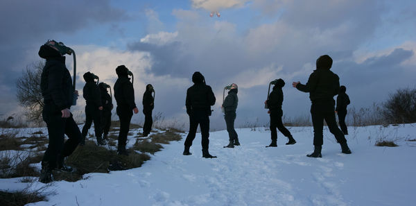 People on snow covered land against sky