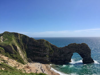 Scenic view of rocks in sea against blue sky