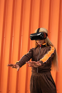 Pretty african american woman using virtual reality glasses on an orange background