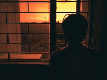 Rear view of man looking through window