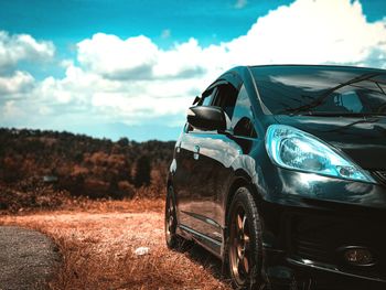 Abandoned car on field against sky