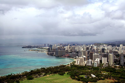 Sea by cityscape against sky