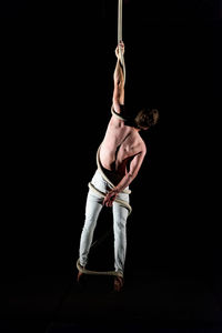 Young man doing gymnastics against black background