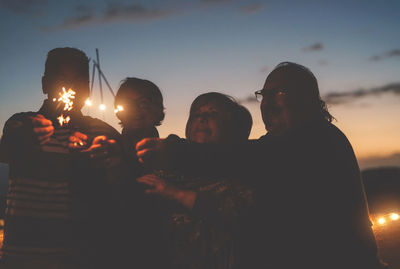 Senior couples holding illuminated sparklers during sunset