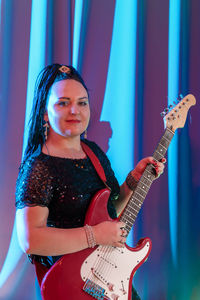 Portrait of young woman playing guitar