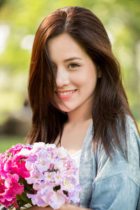 Portrait of smiling young woman with red flower