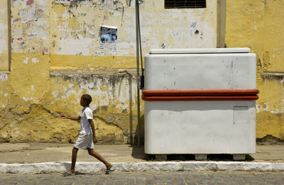 Side view of boy on sidewalk against building