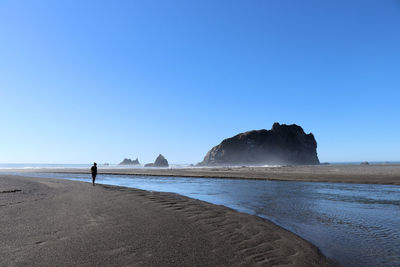 Full length of woman on beach against clear blue sky