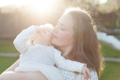 Mother carrying daughter in park during sunny day