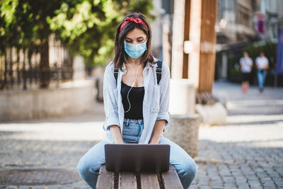 Young woman using laptop on footpath