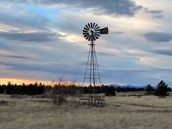 Traditional windmill on field against sky during sunset
